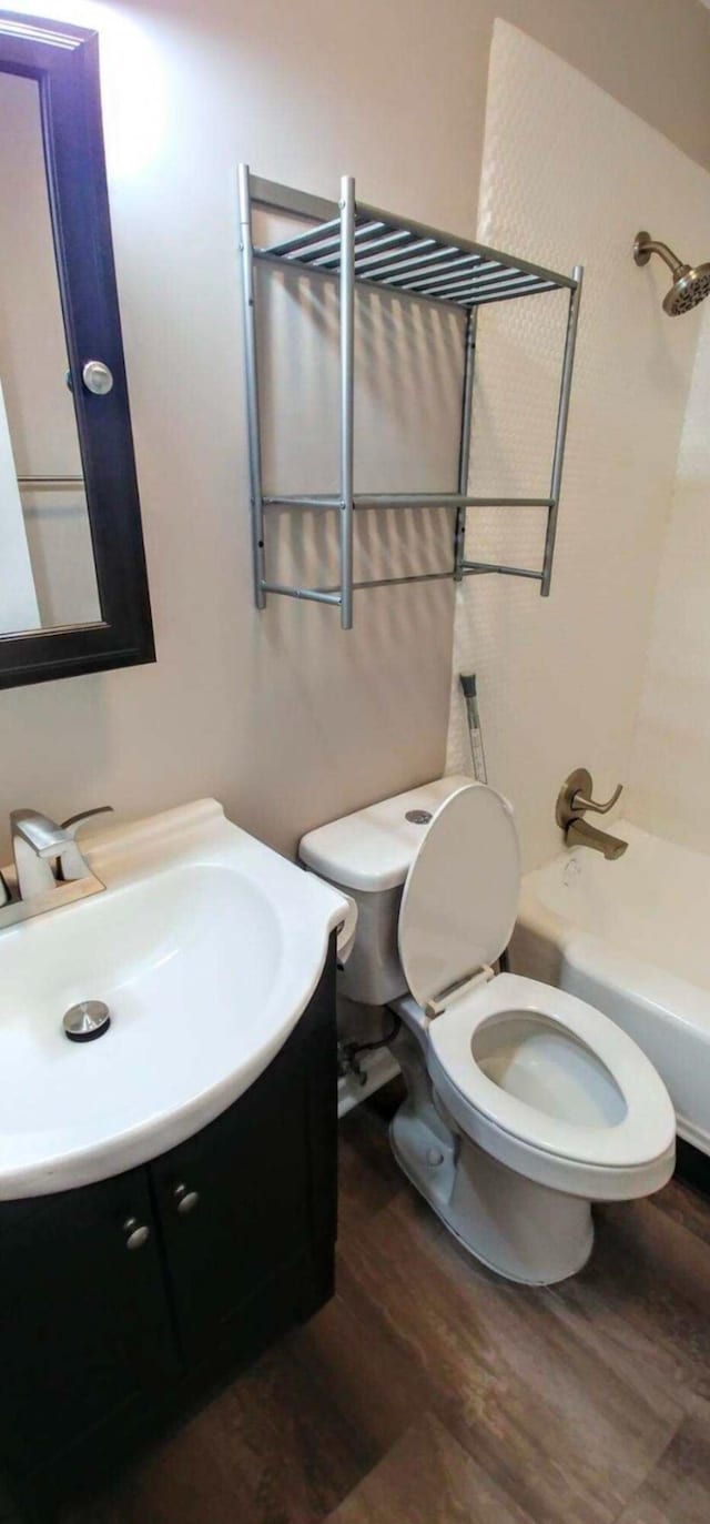 bathroom featuring shower / washtub combination, toilet, vanity, and wood finished floors