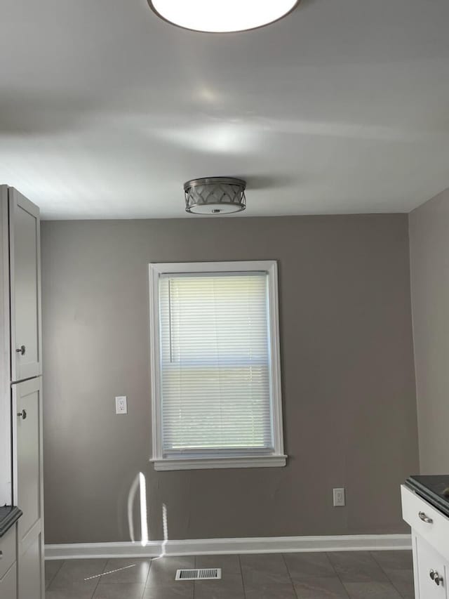 kitchen with visible vents, baseboards, and dark tile patterned flooring