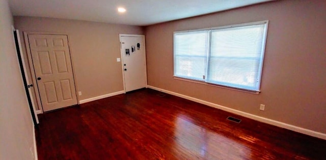 spare room featuring visible vents, baseboards, and wood finished floors