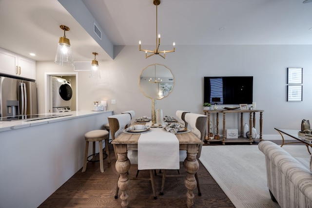 dining room featuring wood finished floors, visible vents, stacked washer and clothes dryer, and a chandelier