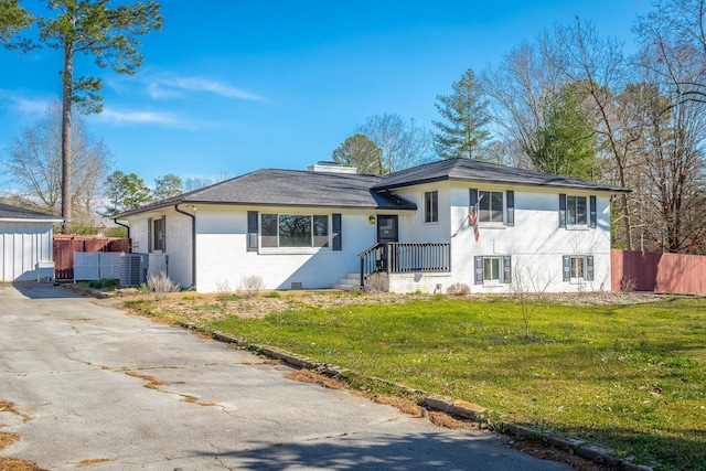 split level home featuring brick siding, central air condition unit, a front yard, and fence