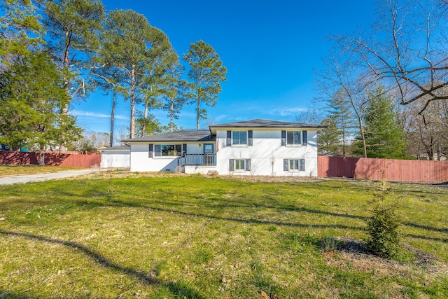 tri-level home with a front yard, fence, and stucco siding