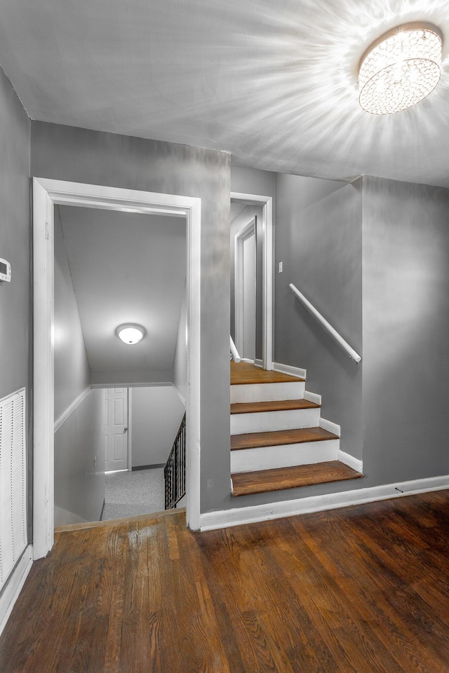 stairs with visible vents, baseboards, and wood finished floors