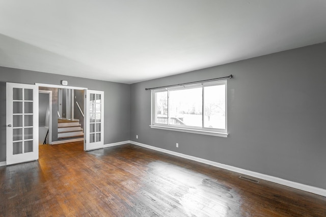 unfurnished room with visible vents, wood finished floors, french doors, stairway, and baseboards