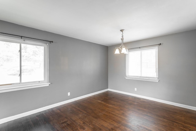 unfurnished room with dark wood-style floors, visible vents, a chandelier, and baseboards