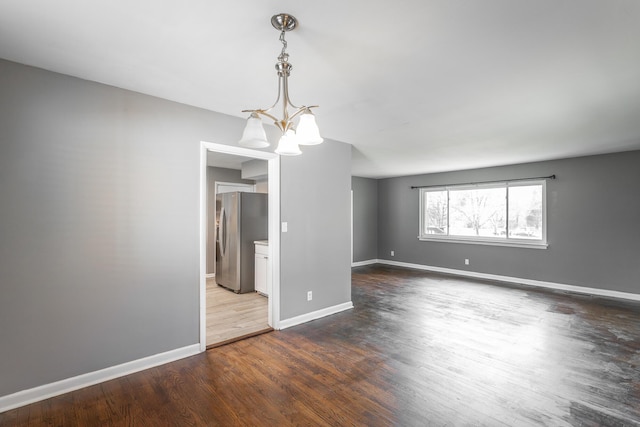 empty room with baseboards, dark wood-style flooring, and a chandelier