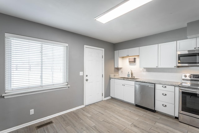 kitchen featuring visible vents, white cabinets, stainless steel appliances, and a sink