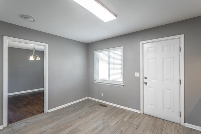 foyer with light wood finished floors, visible vents, baseboards, and an inviting chandelier