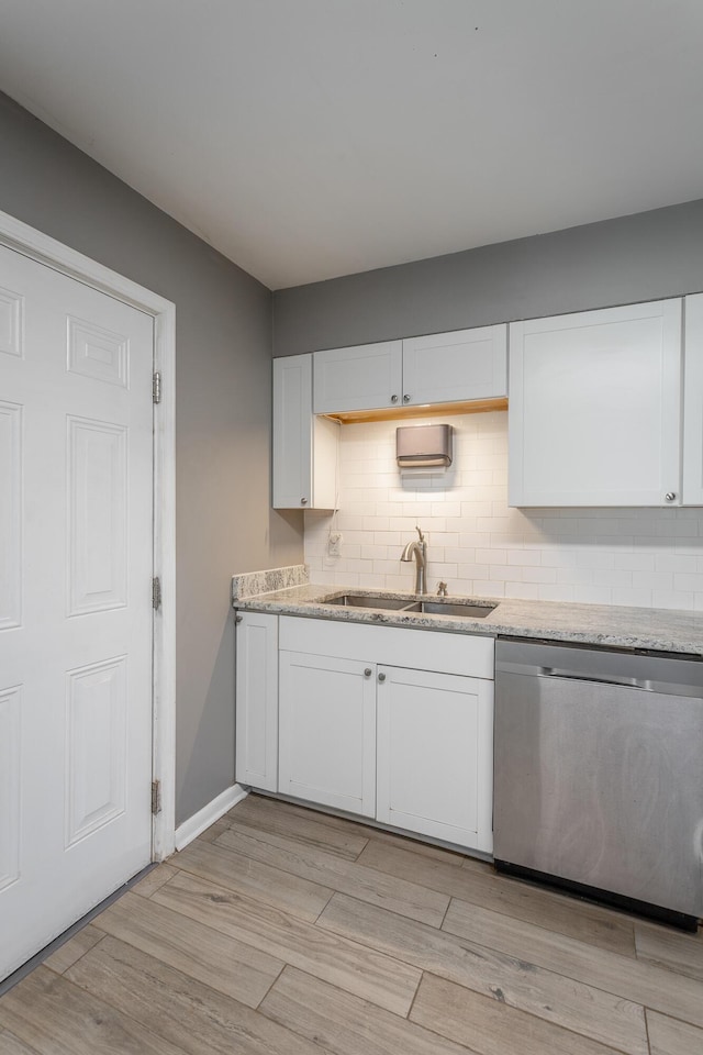 kitchen featuring backsplash, dishwasher, light wood-type flooring, white cabinetry, and a sink