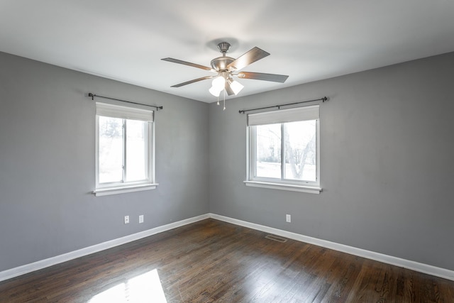 unfurnished room featuring dark wood-style floors, baseboards, and a wealth of natural light