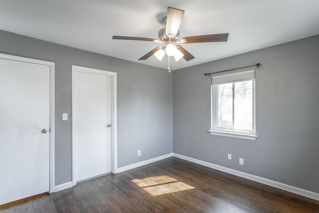 unfurnished bedroom with baseboards, dark wood-style floors, and a ceiling fan