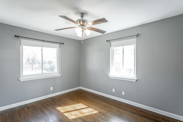 spare room with a wealth of natural light, dark wood-type flooring, and baseboards