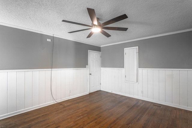 unfurnished room with visible vents, a textured ceiling, a wainscoted wall, and wood finished floors