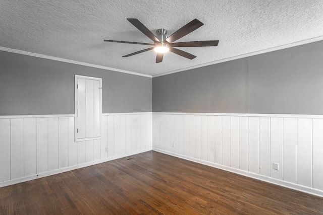 unfurnished room with ornamental molding, a ceiling fan, a textured ceiling, wood finished floors, and wainscoting