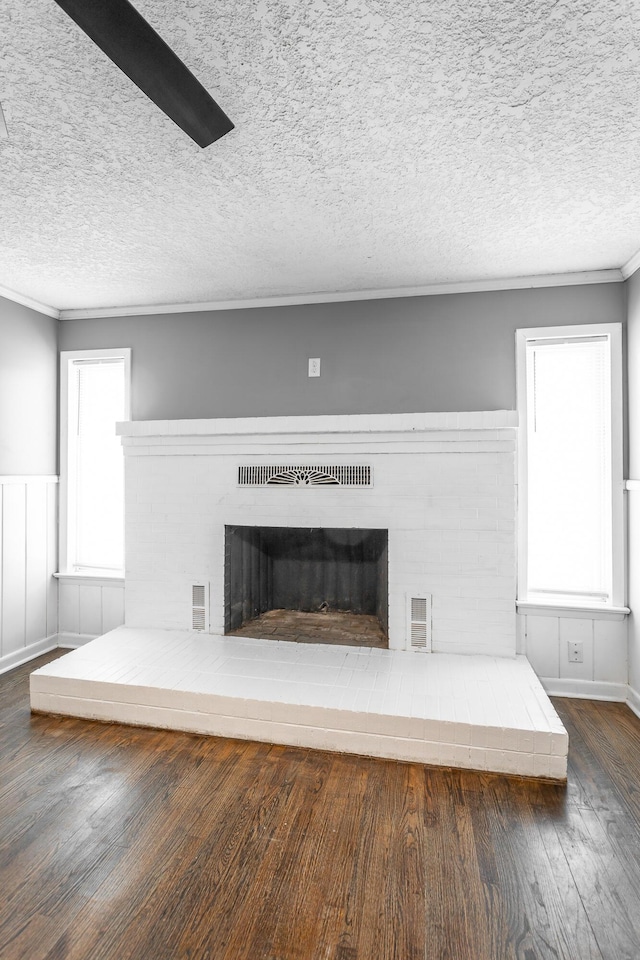 details with a textured ceiling, a brick fireplace, wood finished floors, and ornamental molding