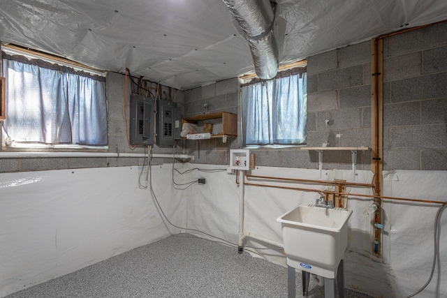 basement featuring electric panel, concrete block wall, and a sink