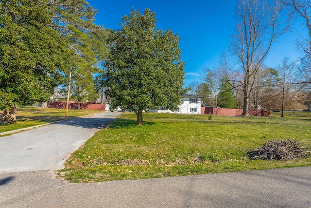 view of front of house with driveway, a front lawn, and fence