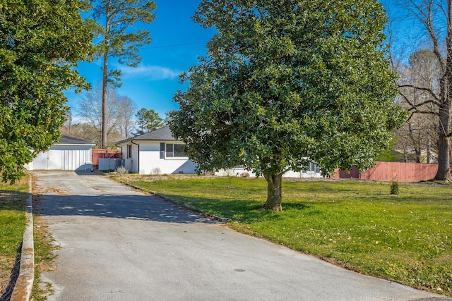 view of front of home with aphalt driveway, a front lawn, and fence