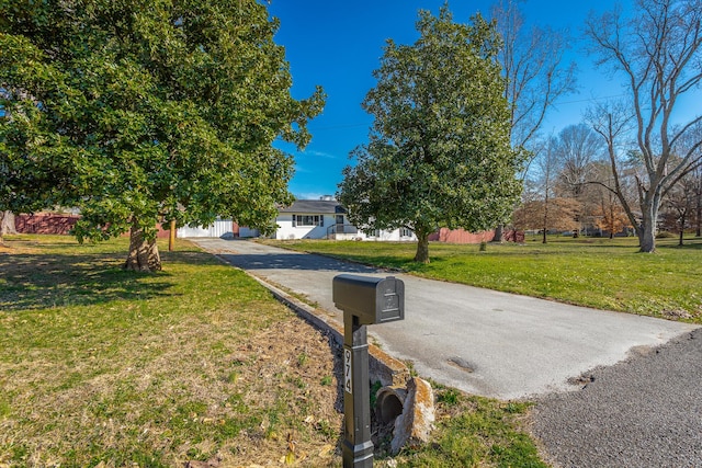 view of front facade with driveway, a front yard, and fence