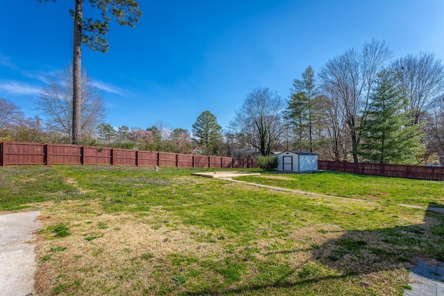 view of yard featuring a storage shed, a fenced backyard, and an outdoor structure