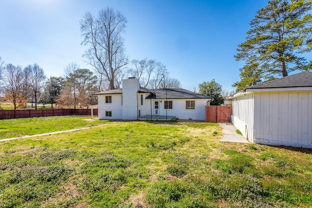 rear view of property featuring a lawn, a chimney, and a fenced backyard