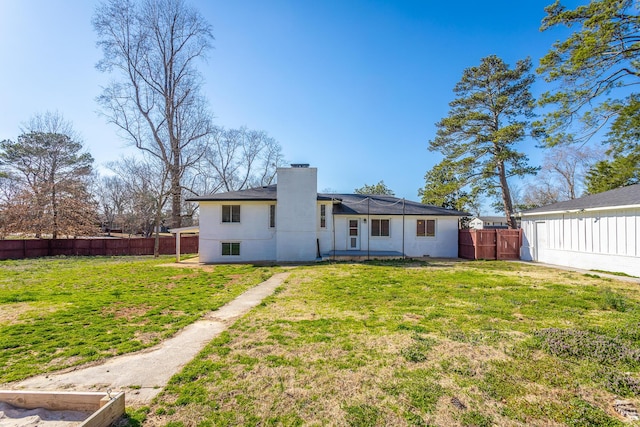 back of property with a yard, a fenced backyard, and a chimney