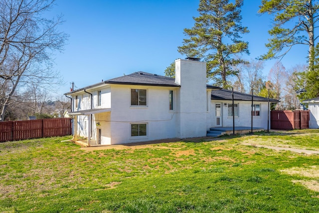 back of house featuring a chimney, a lawn, fence private yard, and brick siding