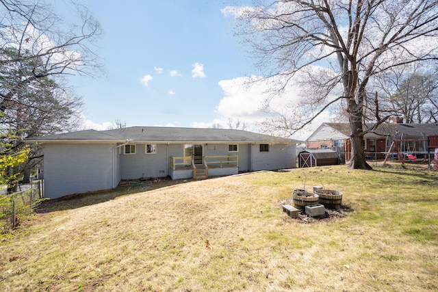 back of house featuring a lawn, brick siding, and fence