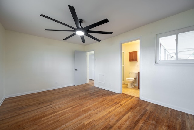 unfurnished bedroom with baseboards, ensuite bath, wood finished floors, and a ceiling fan