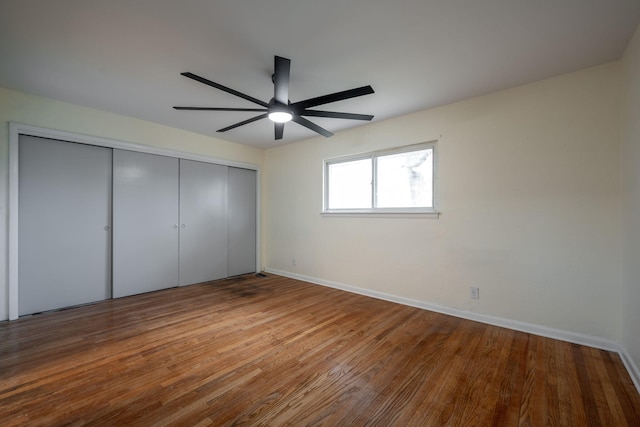 unfurnished bedroom with a closet, a ceiling fan, baseboards, and wood finished floors