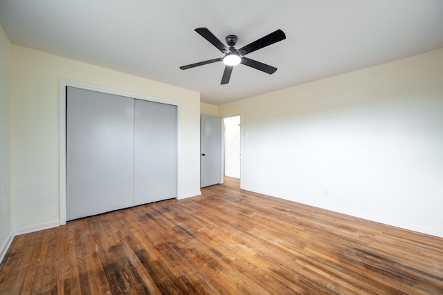 unfurnished bedroom with a closet, a ceiling fan, baseboards, and wood finished floors