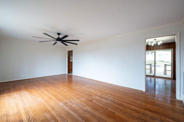 spare room featuring baseboards, wood finished floors, crown molding, and ceiling fan with notable chandelier