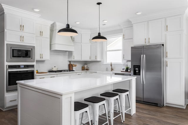 kitchen featuring a center island, dark wood-type flooring, custom range hood, stainless steel appliances, and white cabinetry