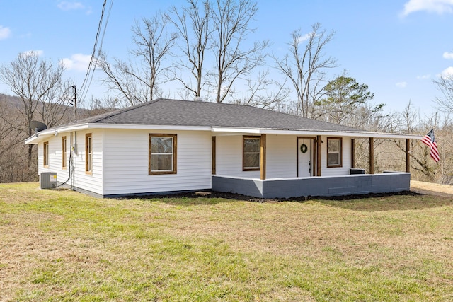 view of front of home featuring a front yard, central air condition unit, covered porch, and a shingled roof