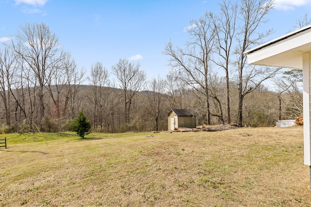 view of yard with an outdoor structure, a wooded view, and a shed