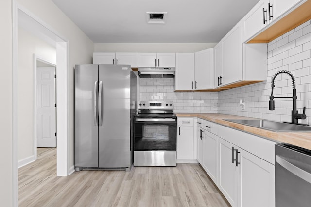 kitchen with a sink, stainless steel appliances, under cabinet range hood, and white cabinets