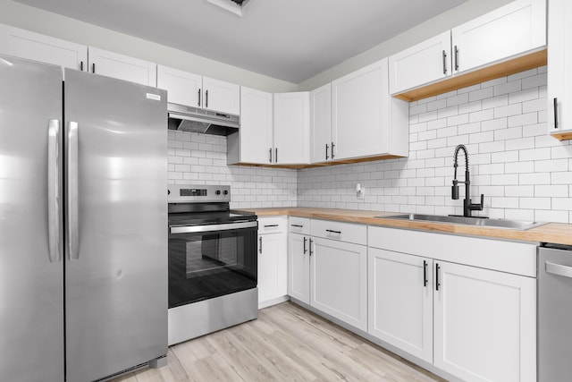 kitchen featuring a sink, wooden counters, appliances with stainless steel finishes, and under cabinet range hood