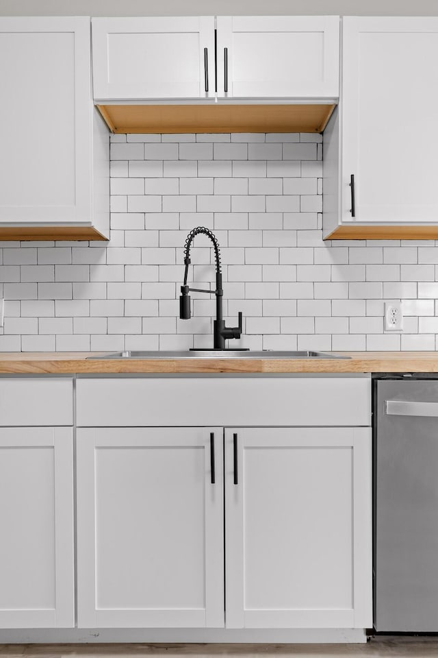 interior space with dishwasher, decorative backsplash, white cabinets, and wooden counters