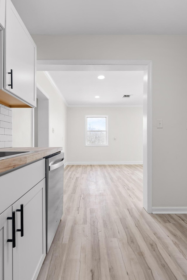 kitchen with light wood-type flooring, stainless steel dishwasher, white cabinets, crown molding, and baseboards