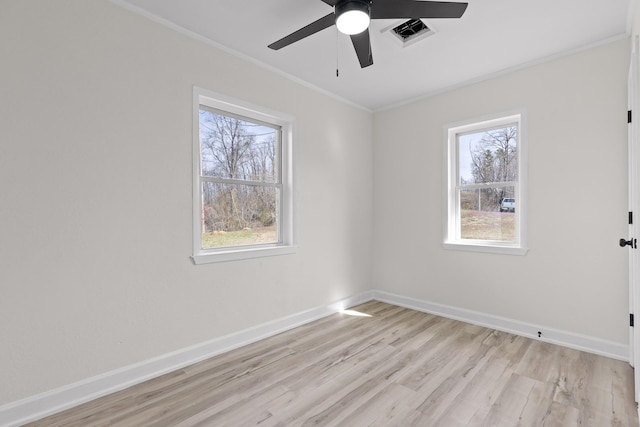 spare room featuring a wealth of natural light, visible vents, baseboards, and crown molding