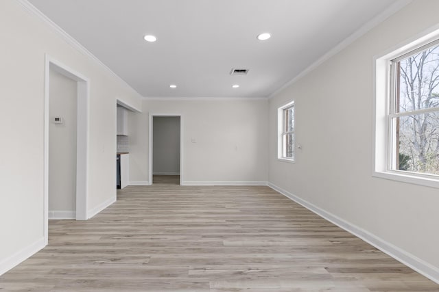 empty room with a wealth of natural light, visible vents, and crown molding