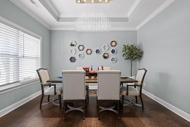 dining room featuring a raised ceiling, an inviting chandelier, wood finished floors, and crown molding