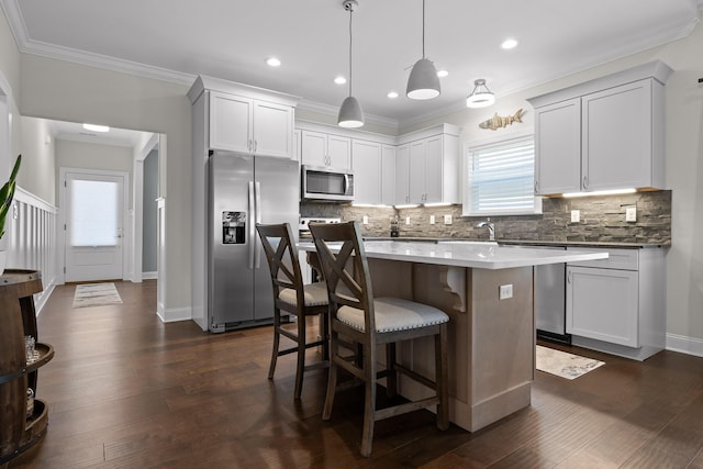 kitchen featuring backsplash, appliances with stainless steel finishes, a center island, and dark wood-type flooring