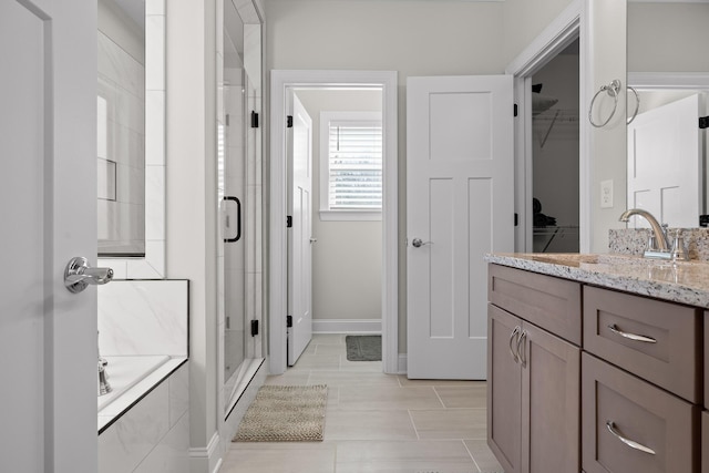 full bath featuring vanity, a shower stall, a walk in closet, and a tub to relax in