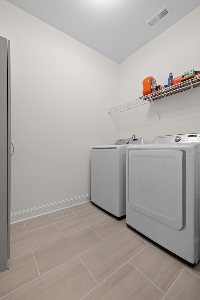 laundry room featuring laundry area, baseboards, visible vents, and washing machine and clothes dryer