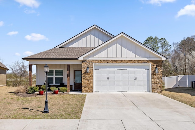 view of front of home with a gate, stone siding, board and batten siding, a shingled roof, and a garage