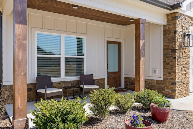 view of exterior entry with stone siding, a porch, and board and batten siding