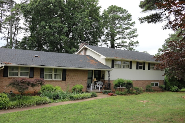 split level home featuring a front lawn, a porch, a shingled roof, brick siding, and a chimney