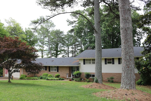 split level home with a front yard, roof with shingles, a chimney, a garage, and brick siding