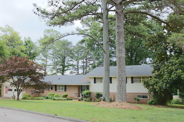 tri-level home with brick siding, a chimney, and a front lawn